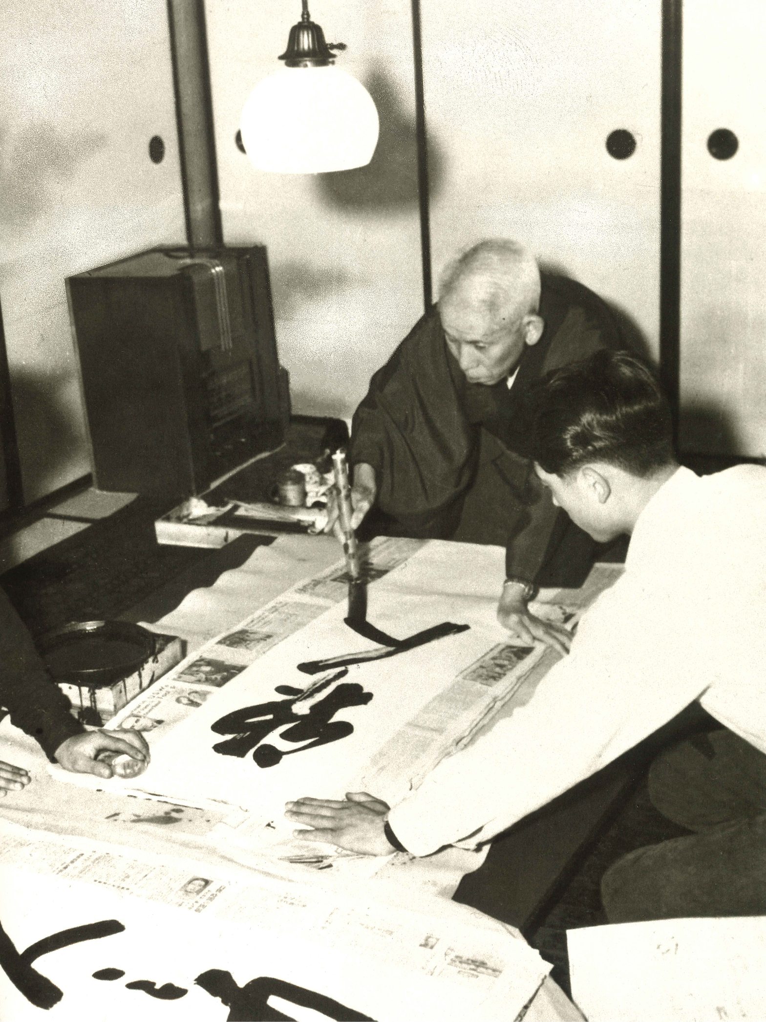 Writing calligraphy with a superhuman speed with the help of those who served Meishu-sama closely. (May 1949, Shimizu-cho Betsu-in, Atami City)